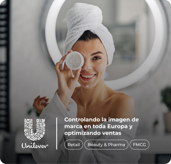 Mujer frente a un espejo, con una toalla envuelta en el cabello y una bata de baño, aplicándose crema facial mientras sonríe. Texto superpuesto: "Controlando la imagen de marca en toda Europa y optimizando ventas. Retail, Beauty & Pharma, FMCG". Logotipo de Unilever en la esquina inferior izquierda.